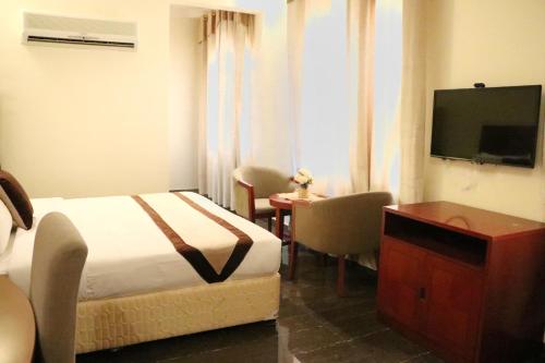 塞拉莱Rimal Suites Apartments的配有一张床和一台平面电视的酒店客房