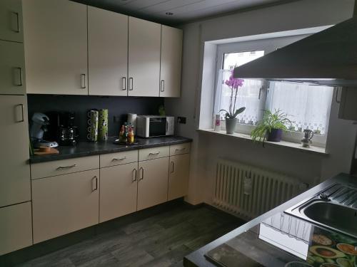 考夫博伊伦Ferienhaus CasaNoWa的厨房配有白色橱柜、水槽和窗户。