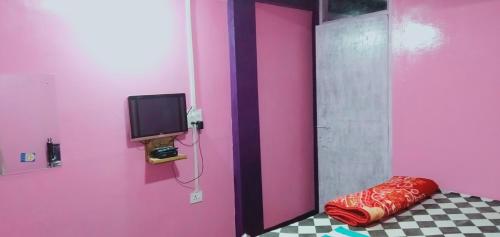 乞拉朋齐Shalom guest house的一间设有粉红色墙壁、电视和枕头的客房