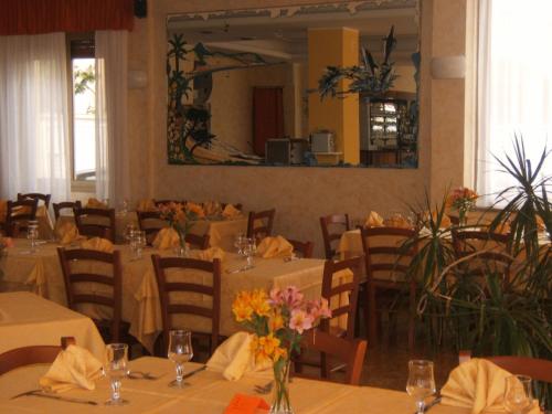 莱圭利亚Hotel Delfino的餐厅设有桌椅,并种有鲜花