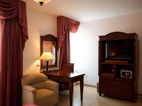 卡门城皇家庄园酒店的酒店客房配有书桌、椅子和电视。