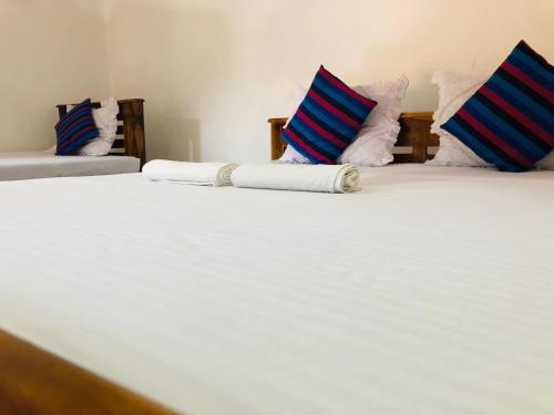 波隆纳鲁沃Kumari Guest House的两张带蓝色和白色枕头的床