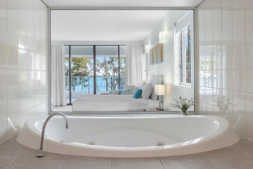 棕榈湾Drift Palm Cove的白色的浴室设有浴缸和床。