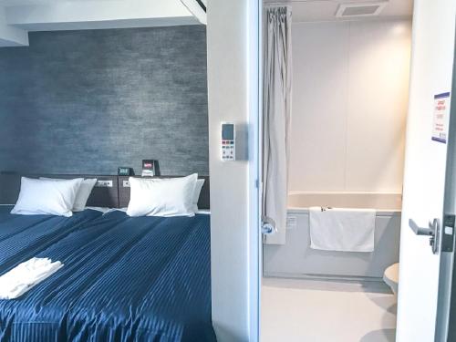 郡山Hotel Livemax Fukushima Koriyama的一间卧室配有一张带蓝色床单和白色枕头的床。