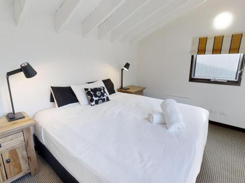 佩里舍峡谷Studio Loft 19 The Stables Perisher的卧室设有一张白色大床和一扇窗户。