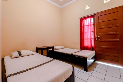 KalasanGriya Barokah的客房设有两张床和一个带红色窗帘的窗户。
