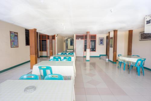 LhokseumaweOYO 2180 Vina Vira Hotel的一间设有几张桌子和蓝色椅子的房间