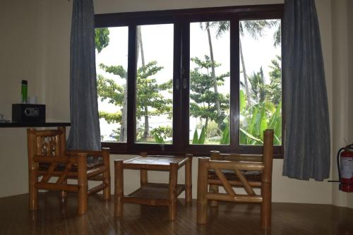 卢纳将军城Jonas and Twins Resort的一间带桌椅和大窗户的用餐室