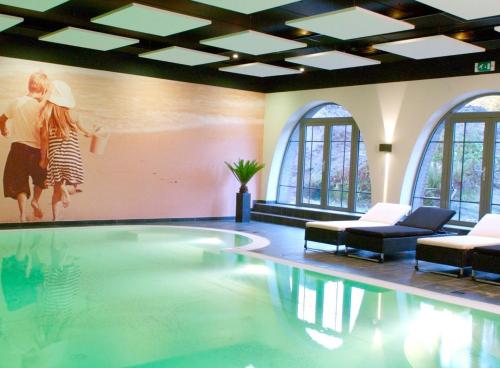 霍斯特霍斯特 - 芬洛公园酒店的一个带两把椅子的游泳池,墙上有一幅画