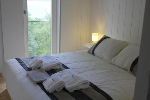 AntigoMoinhos da Corga的一张带毛巾的白色床,设有窗户
