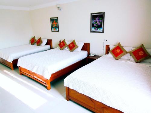 洞海Hoang Dat Hotel的客房配有2张带白色和红色枕头的床。