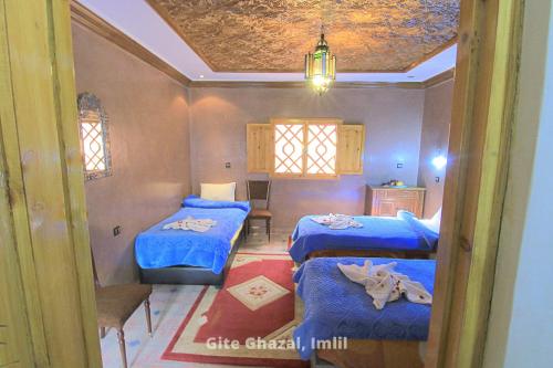 伊姆利尔Gite Ghazal - Atlas Mountains Hotel的一间设有两张带蓝色床单的床的房间