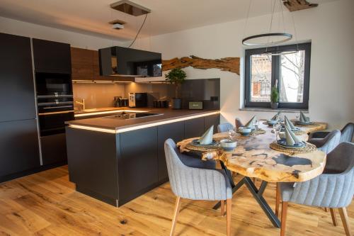 加尔米施-帕滕基兴Apartment Wood&Stone Alpi的一间带木桌和椅子的厨房和一间带黑色橱柜的厨房