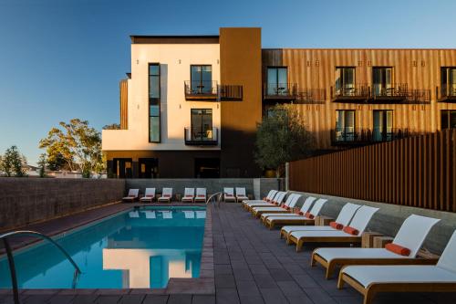 圣路易斯-奥比斯保Hotel San Luis Obispo的一座带躺椅的游泳池位于大楼旁
