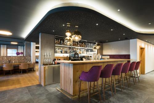 阿尔卑巴赫Boutiquehotel die Alpbacherin的餐厅内带紫色酒吧凳的酒吧