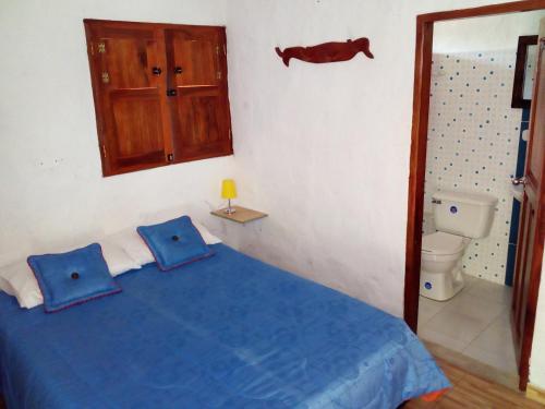 贾丁Hostal Encanto La Salada的一间卧室设有蓝色的床和卫生间