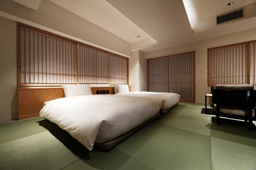 东京PROSTYLE RYOKAN TOKYO ASAKUSA的卧室配有一张白色大床和一把椅子