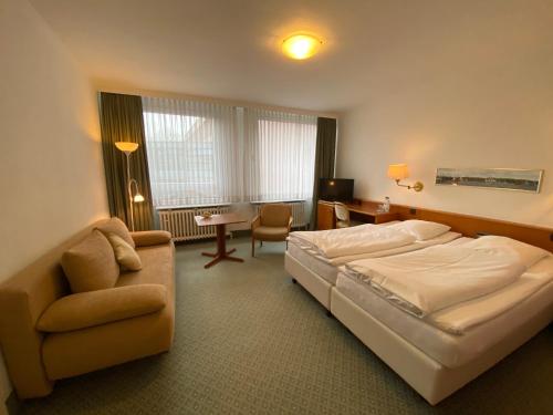 弗伦斯堡菲勒斯伯格酒店的一间卧室配有一张床、一把椅子和一张沙发