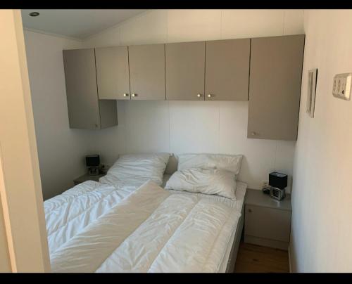 沙博伊茨Beach Chalet SunHus - modernes Chalet in Ostseenähe的一间卧室配有两张带白色床单和橱柜的床。