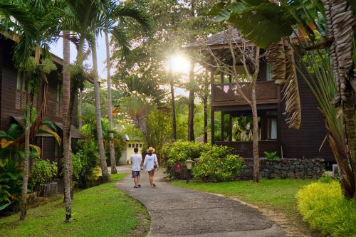 珍南海滩Rebak Island Resort & Marina, Langkawi的男人和女人在房子前面的小路前走