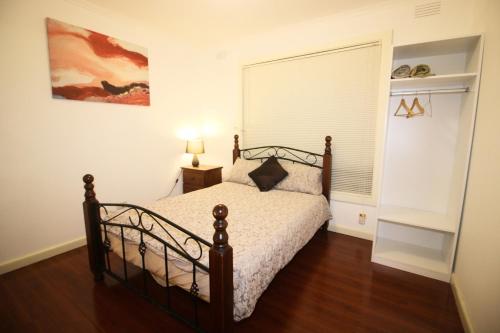 墨尔本Sunny House - Melbourne Airport Home的一间卧室配有一张铺有木地板的床。