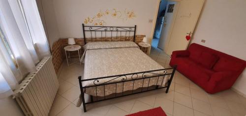 尼阿博勒皮耶韦La Casina di Zia Zita的一间卧室配有一张床和一张红色的沙发