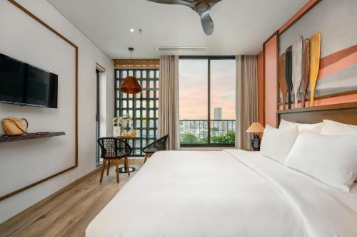 岘港Seahorse Tropical Da Nang Hotel by Haviland的卧室设有一张白色大床和大窗户