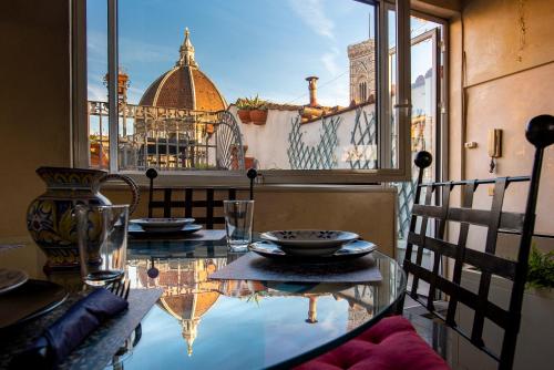 佛罗伦萨Borgo San Lorenzo Attico Duomo的玻璃桌,从窗户可欣赏到建筑的景色