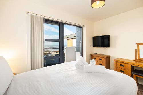 韦斯特沃德霍West Beach - Holiday Apartments的卧室设有白色的床和大窗户