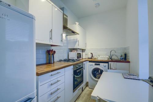 普雷斯蒂克Garden Gate Upper Apartment的厨房配有白色橱柜、洗衣机和烘干机