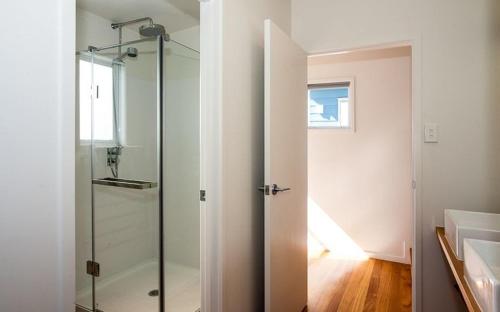 图图卡卡Shoreside - Tutukaka Holiday Home的一个带水槽的浴室内的玻璃淋浴间门