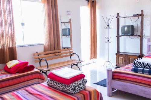 Resende CostaPousada DDB的客房设有两张床、一张长凳和一台电视。