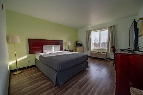 科罗拉多斯普林斯Rodeway Inn Central Colorado Springs的一间卧室设有一张床和一个大窗户