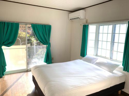 鹿儿岛GANADAN Cottage的一间卧室配有一张带绿色窗帘的床和窗户。