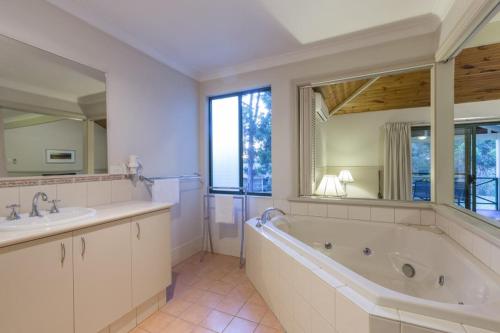 玛格丽特河布希湖小木屋酒店的带浴缸、两个盥洗盆和大镜子的浴室