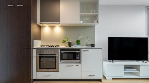 墨尔本Oaks Melbourne Southbank Suites的一间带炉灶的厨房和一台电视