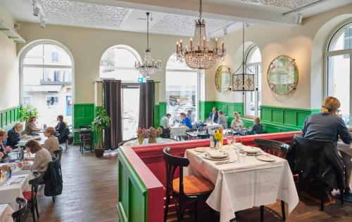 苏黎世普拉特恩霍夫设计酒店的一间设有桌子的餐厅,有坐在桌子上的人