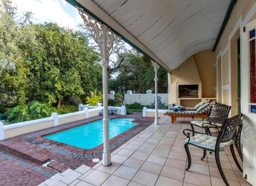 斯泰伦博斯埃弗格林旅馆的庭院设有游泳池、桌子和椅子。