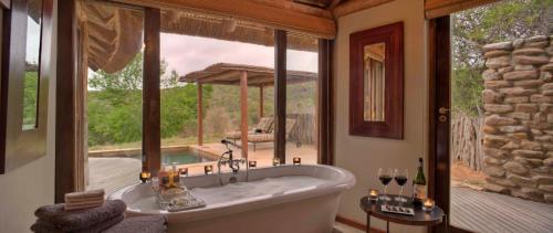格拉罕镇Kwandwe Great Fish River Lodge的设有一个大浴缸的大窗户