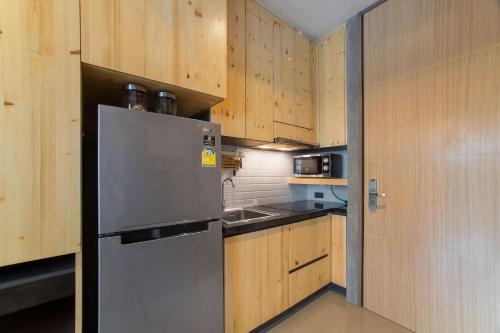 奈汉海滩Студия на пляже Най Харн B227 от IBG Property的厨房配有不锈钢冰箱和木制橱柜