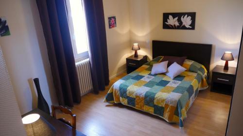 Montpon-MénestérolHOTEL Restaurant LE CALDERO的一间卧室配有一张带五颜六色棉被的床