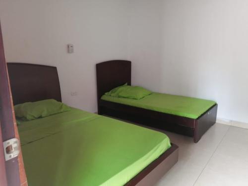 里考尔特Hotel Mar Y Luna Eventos的配有绿床单的客房内的两张床