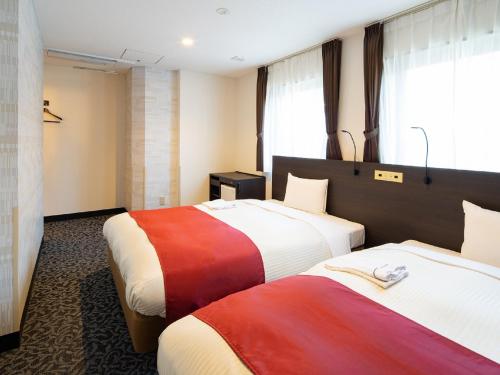 东京Ai Hotel Keikyu Kamata的两张位于酒店客房内的床铺,配有色彩缤纷的床单
