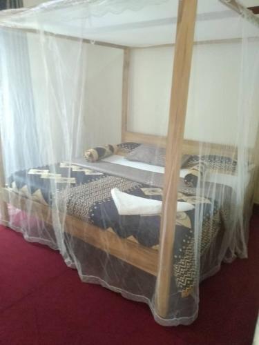 恩德培KERESI BUDGET BLOCK at PENIEL的一间卧室配有带蚊帐的天蓬床。
