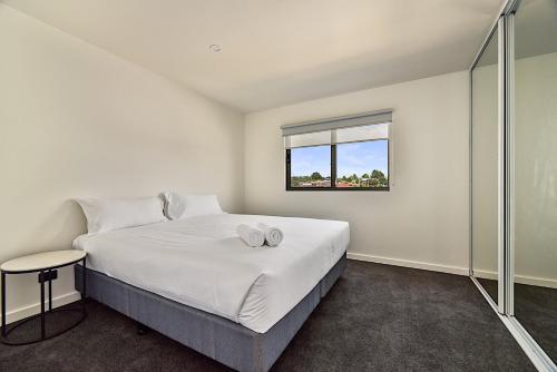 朗塞斯顿Southern Apartments Launceston的白色的卧室设有床和窗户