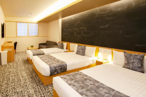 名古屋GRAND BASE Osu的一间设有三张床的客房,墙上设有一张黑板