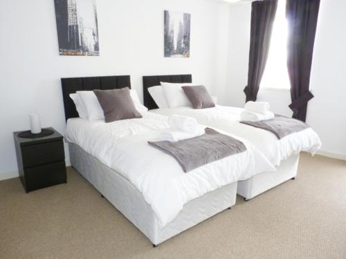 邓凯尔德8 Cathedral Street的一间卧室配有两张床、白色床单和灰色枕头。