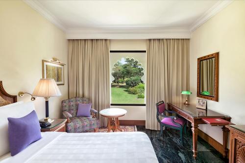 乌代浦乌代浦三叉戟酒店的配有一张床和一张书桌的酒店客房