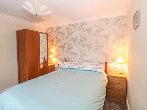 HenstridgeFrodos的一间卧室配有一张床、两个床头柜和两盏灯。