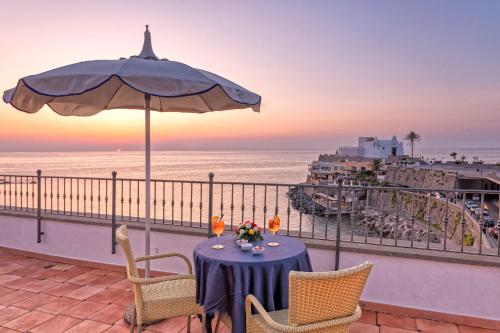 伊斯基亚尼图诺酒店的阳台上的桌子上摆放着遮阳伞和海洋
